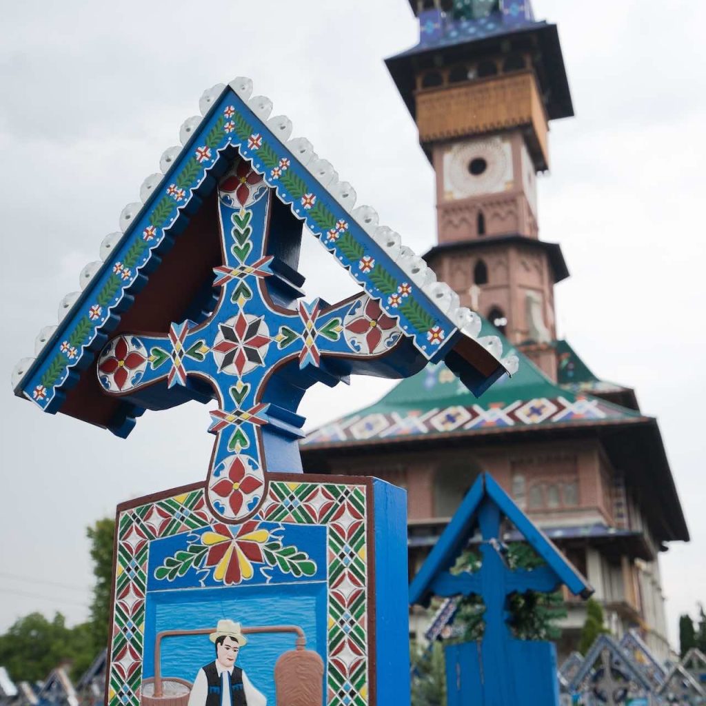 An ornate painted wooden headstone in the Merry Cemetery of Sapanta